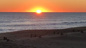 Une plage où le soleil se couche sur l’océan.