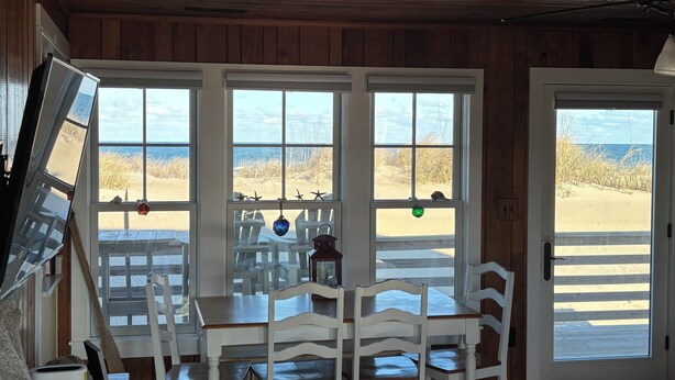 Une pièce au décor intérieur en bois, avec une table et des chaises, et de grandes fenêtres donnant sur une plage.