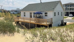 Une maison située en bord de mer, dotée d’une terrasse en bois et d’un espace salon extérieur abrité.