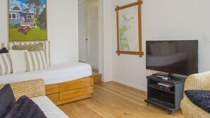 Un salon chaleureux avec un canapé, un meuble pour la télévision et un tableau représentant une maison.