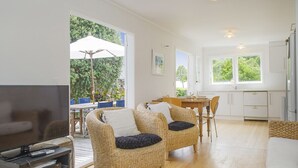 Un vaste espace de vie aménagé avec des meubles en osier, un téléviseur à écran plat et une table à manger.