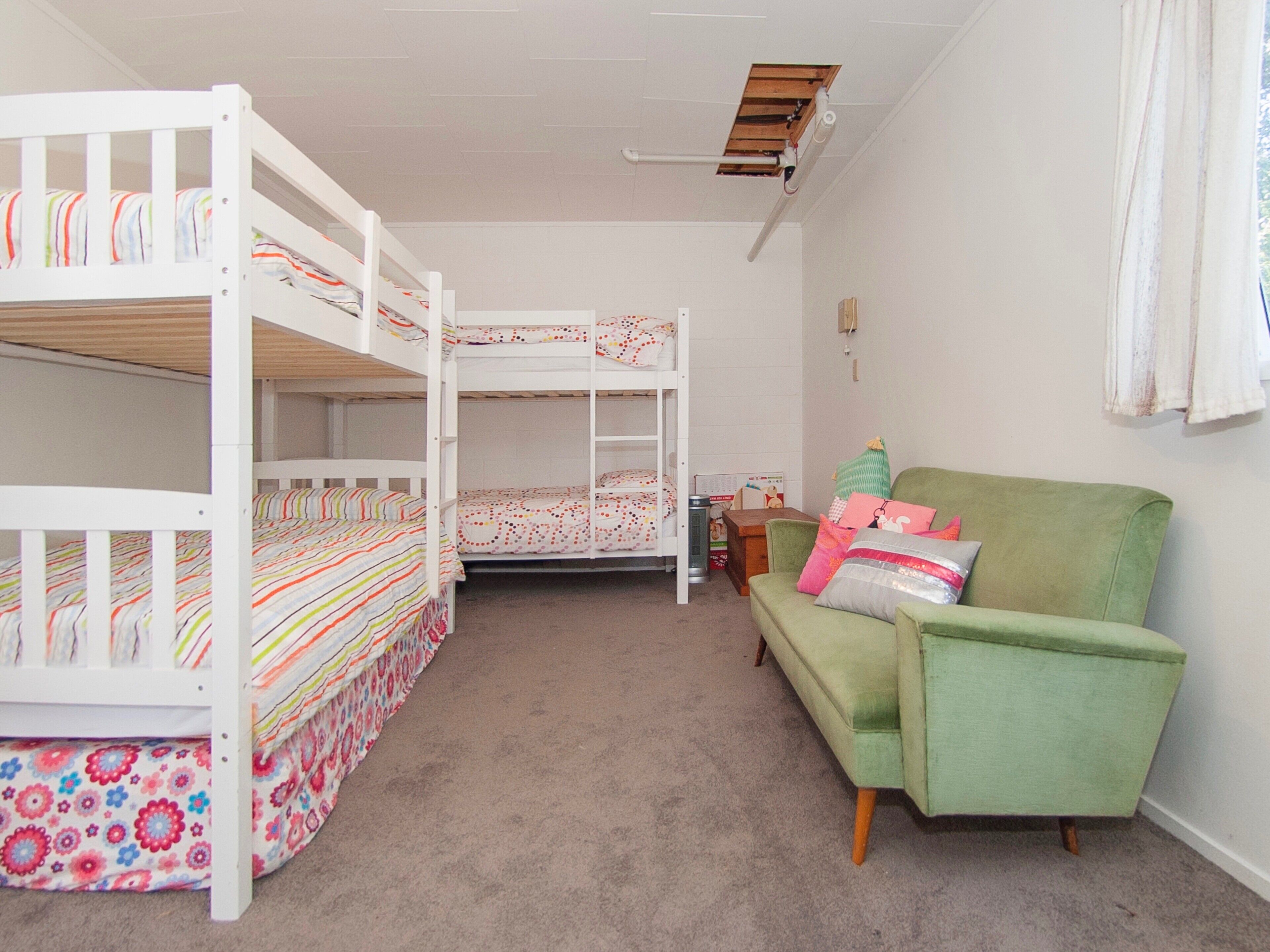 A room with bunk beds, a green sofa, and a small table.