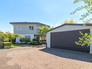 A two-story house with a garage, a paved driveway, and a well-maintained lawn.