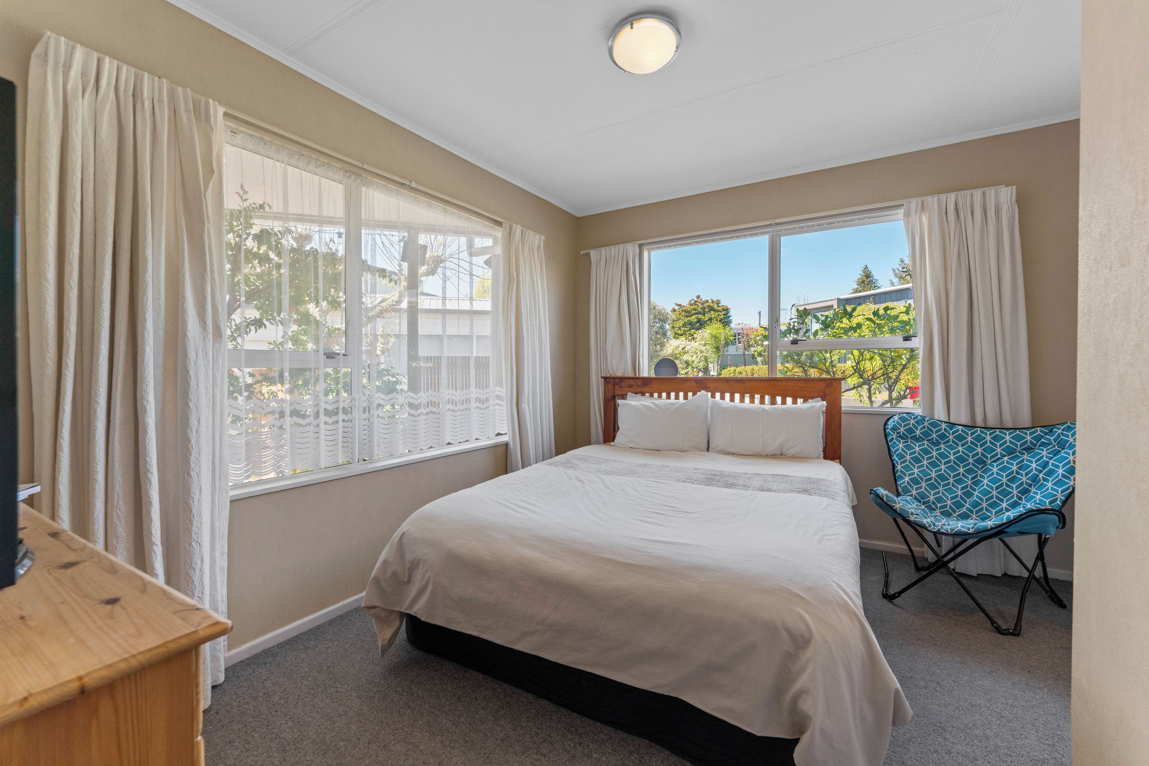 A bedroom with a bed, a chair, and a window with curtains.