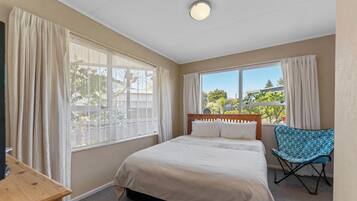 A bedroom with a bed, a chair, and a window with curtains.