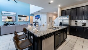 Una cocina moderna con armarios oscuros, un refrigerador de acero inoxidable y una encimera de granito.
