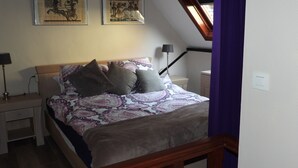 A bedroom with a bed, two bedside tables, a lamp, and two framed pictures on the wall. - Loft in Red Light District (Antwerpen)