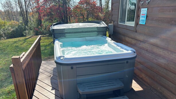 Een jacuzzi op een houten terras, met een houten huis op de achtergrond.