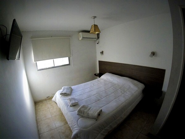 A small, clean room with a single bed, a window, and a ceiling fan. - Estrella Andina (San Juan)