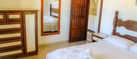Una habitación de hotel con una cama, un aparador de madera, un espejo y un armario.