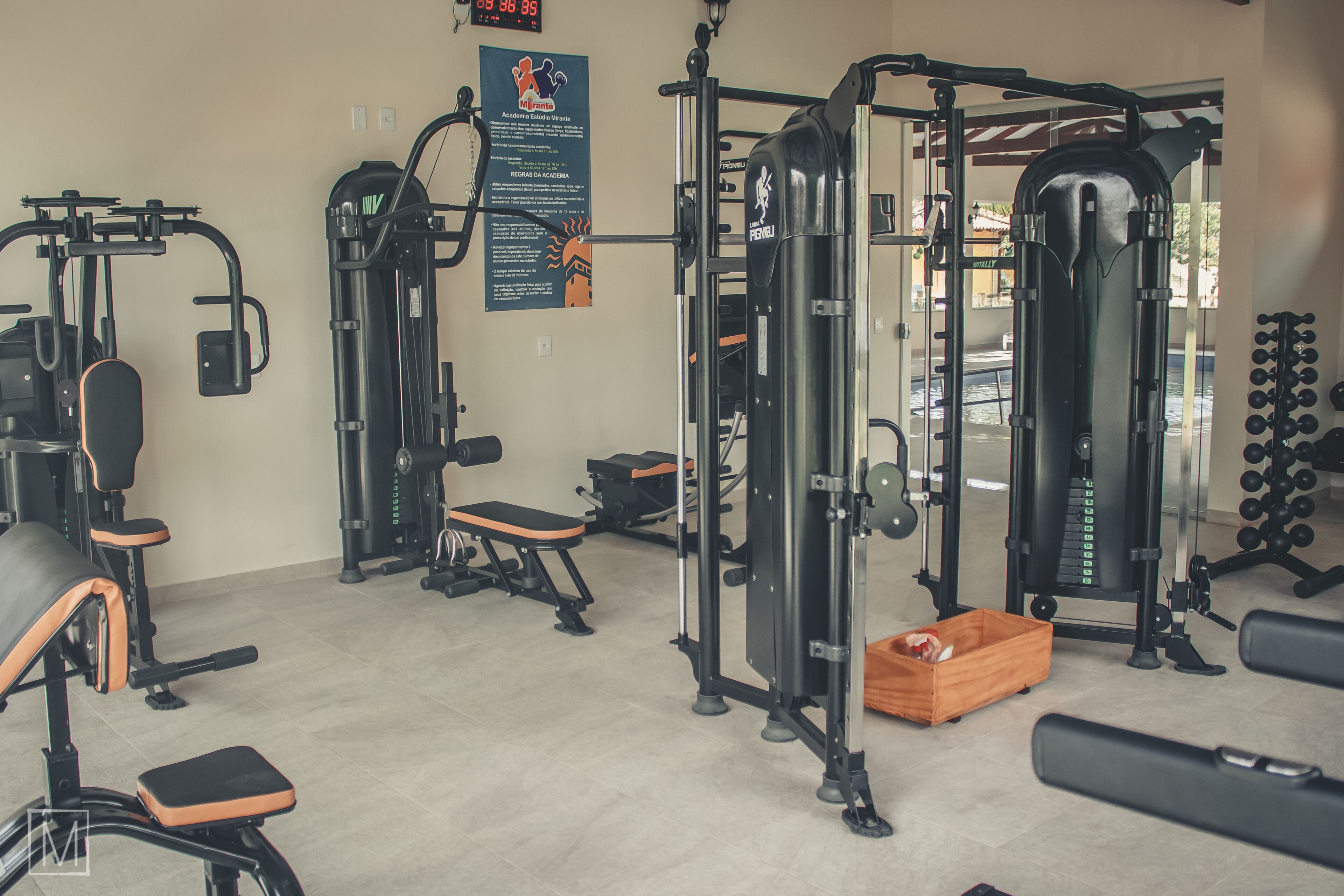 A gym with various exercise equipment, including benches, a squat rack, and dumbbells.