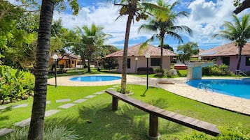 A resort with two swimming pools, palm trees, and a well-maintained lawn.