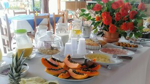 A breakfast buffet with various fruits, pastries, and beverages.