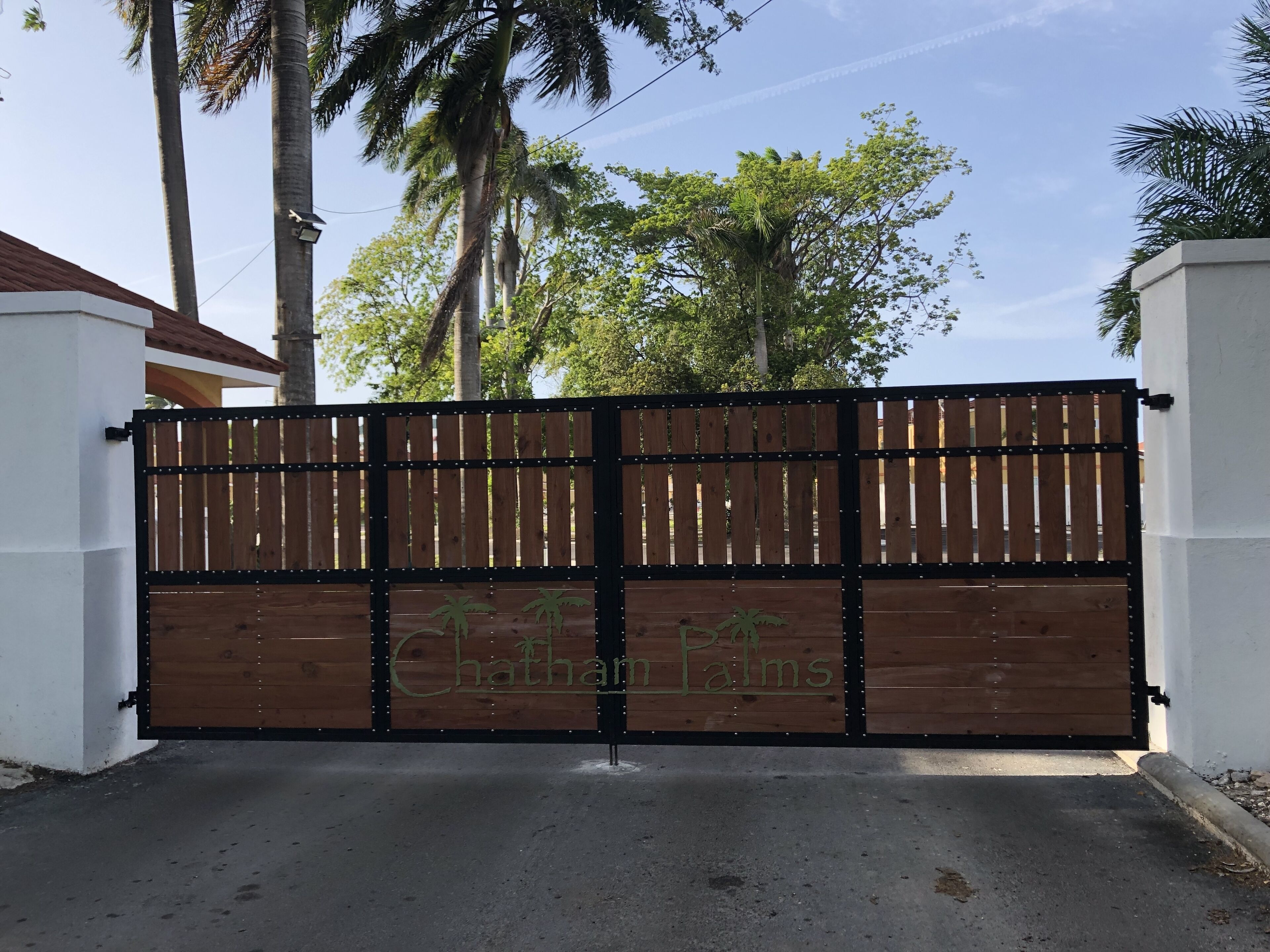 Une entrée fermée par un portail, sur laquelle on peut lire l’inscription « Chathan Palms ».