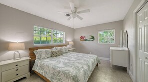 A bedroom with a bed, nightstands, a ceiling fan, and two windows with blinds.