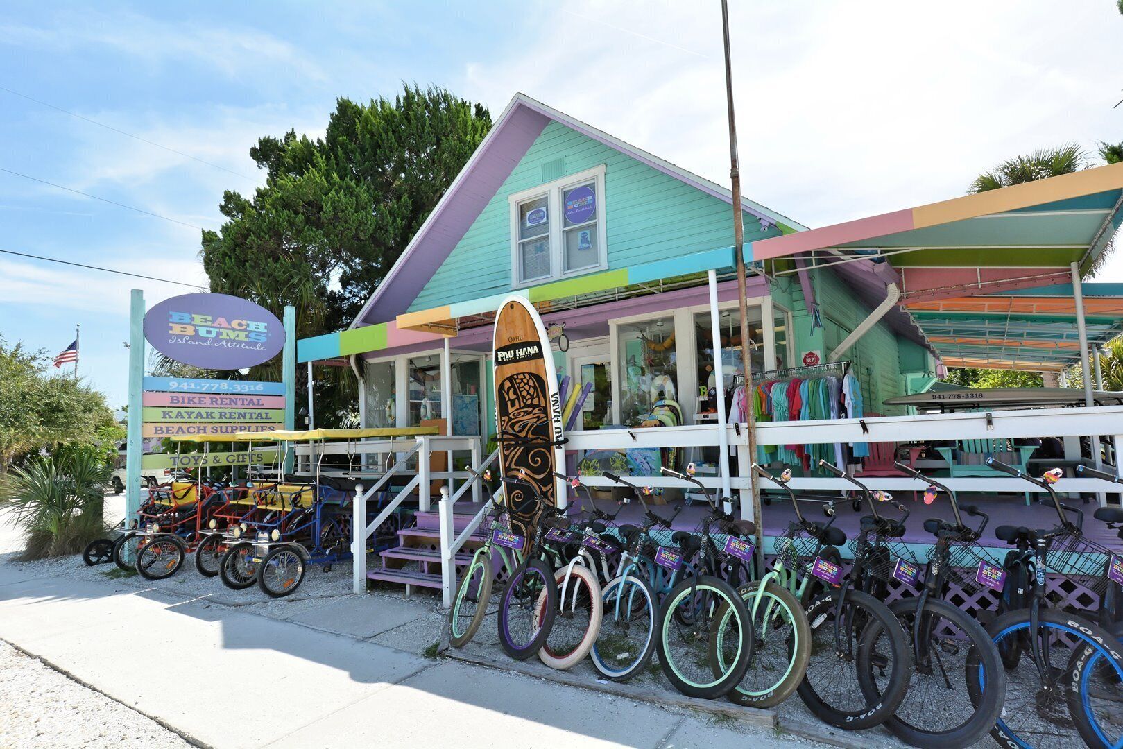 A colorful building with a sign for 'Beach Bums Island Attitude' offering bike and kayak rentals, beach supplies, and toys & gifts.