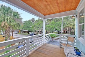 Eine überdachte Veranda mit Holzboden, weißen Geländern und einer Bank.