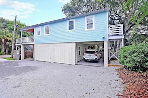 Une maison à deux étages avec un garage, une véranda et un petit balcon.