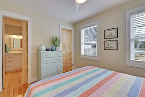 Une chambre à coucher avec un lit, une commode, un placard et des fenêtres.