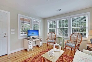 A living room with a television, two wicker chairs, a coffee table, and a patterned rug.