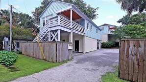 A two-story house with a porch and a staircase leading to the upper floor. - Classic Folly Cottage (Folly Beach)