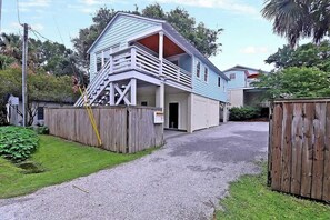 Ein zweigeschossiges Haus mit einer Veranda und einer Treppe, die zu der oberen Etage führt.