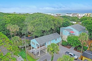 A coastal property with two main buildings, surrounded by dense greenery and a view of the sea. - Classic Folly Cottage (Folly Beach)