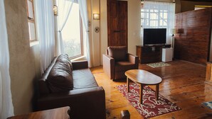 Un salon confortable avec un canapé, une petite table, un téléviseur et une porte en bois.