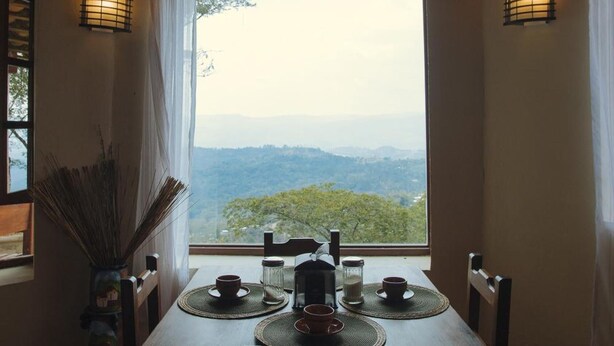 Une table à manger avec des chaises, une vue sur les montagnes et deux lampes fixées au mur.