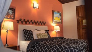 Une chambre à coucher avec un lit, deux lampes de chevet, un luminaire fixé au mur et une porte.