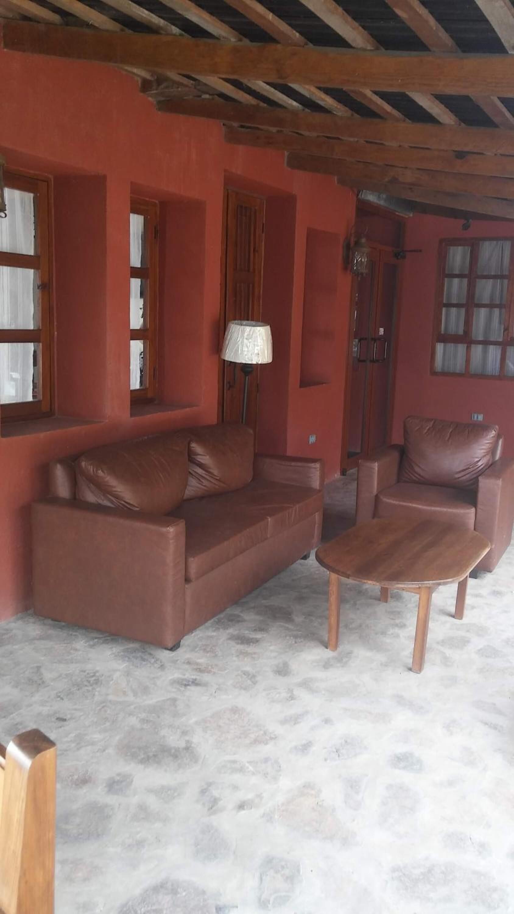 A room with a brown leather sofa, a matching armchair, and a small wooden table.