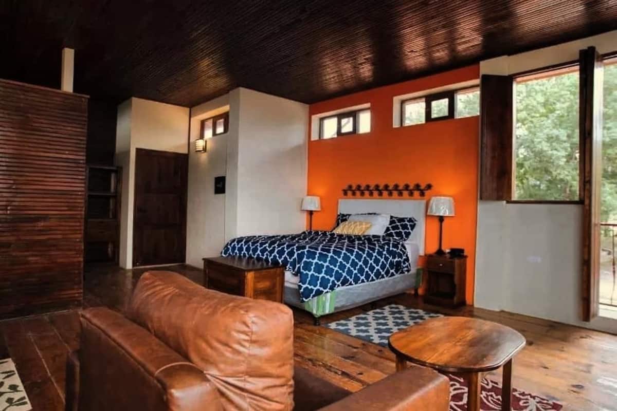 A bedroom with a bed, a wooden headboard, a nightstand, a lamp, and a window.