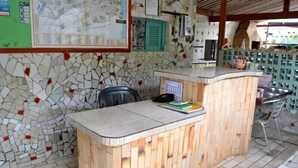 A reception desk with a mosaic wall, a map, and a calendar. - Pousada Porto do Sol (Conde)