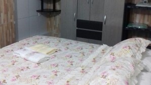 A bedroom with a bed, a wardrobe, and a fan. - Pousada Porto do Sol (Conde)