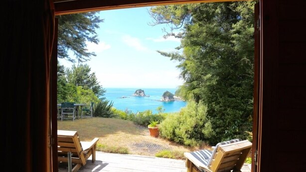 A wooden deck with two lounge chairs facing a scenic view of the ocean and rocky outcrops. - Heart of Kaiteriteri: Absolute Privacy nestled between both beaches  (Kaiteriteri)