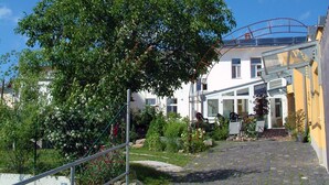 Un pati amb un arbre, un camí pavimentat i un edifici amb façana de vidre.