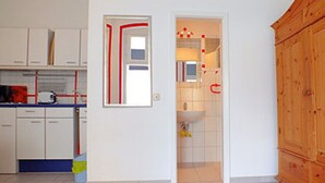 Cuina amb armaris blancs, microones i un armari de fusta.
