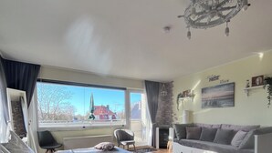 A modern bedroom with a bed, a sofa, a chair, and a large window. - Cozy apartment, Cuxhaven-Döse (Cuxhaven)