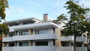 A modern multi-story building with balconies, a parking area, and a street view. - Cozy apartment, Cuxhaven-Döse (Cuxhaven)