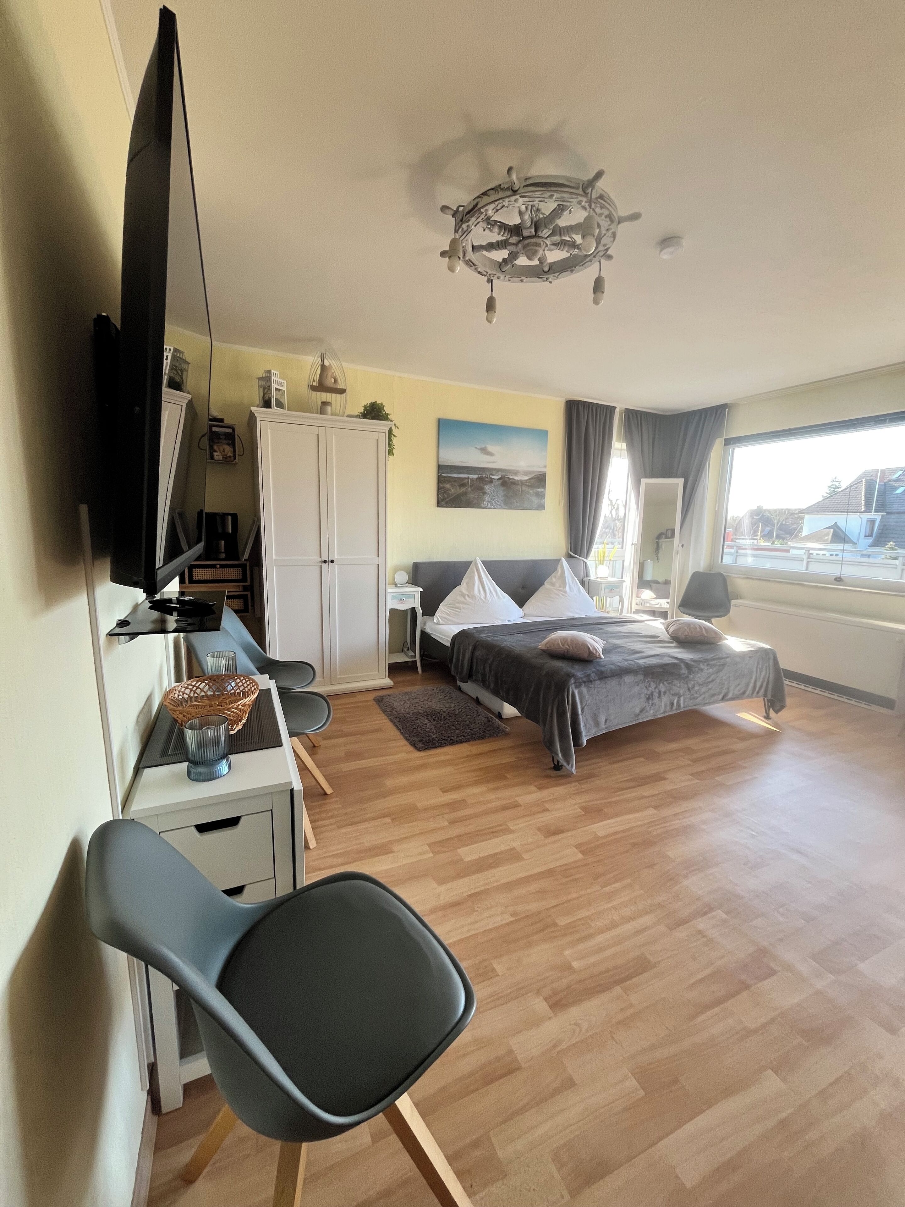 Une chambre à coucher comprenant un lit, un bureau, une chaise, une armoire, un téléviseur et une fenêtre donnant sur un paysage agréable.