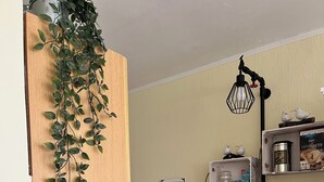 A compact kitchen with a wooden cabinet, a white refrigerator, a coffee maker, a toaster, and a trash bin. - Cozy apartment, Cuxhaven-Döse (Cuxhaven)