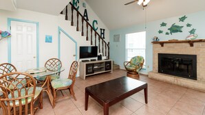 A living room with a staircase, a fireplace, and a television. - Waterfront Escape | Pet-Friendly & Beach Nearby (Corpus Christi)