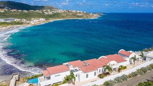 A coastal residential area with white buildings, a swimming pool, and a view of the ocean. - Villa Amalia (Philipsburg)