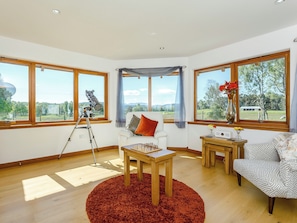 A room with a telescope, a white sofa, a patterned armchair, and a wooden table. - 3 bedroom accommodation in Carrbridge, near Aviemore (Carrbridge, near Aviemore)