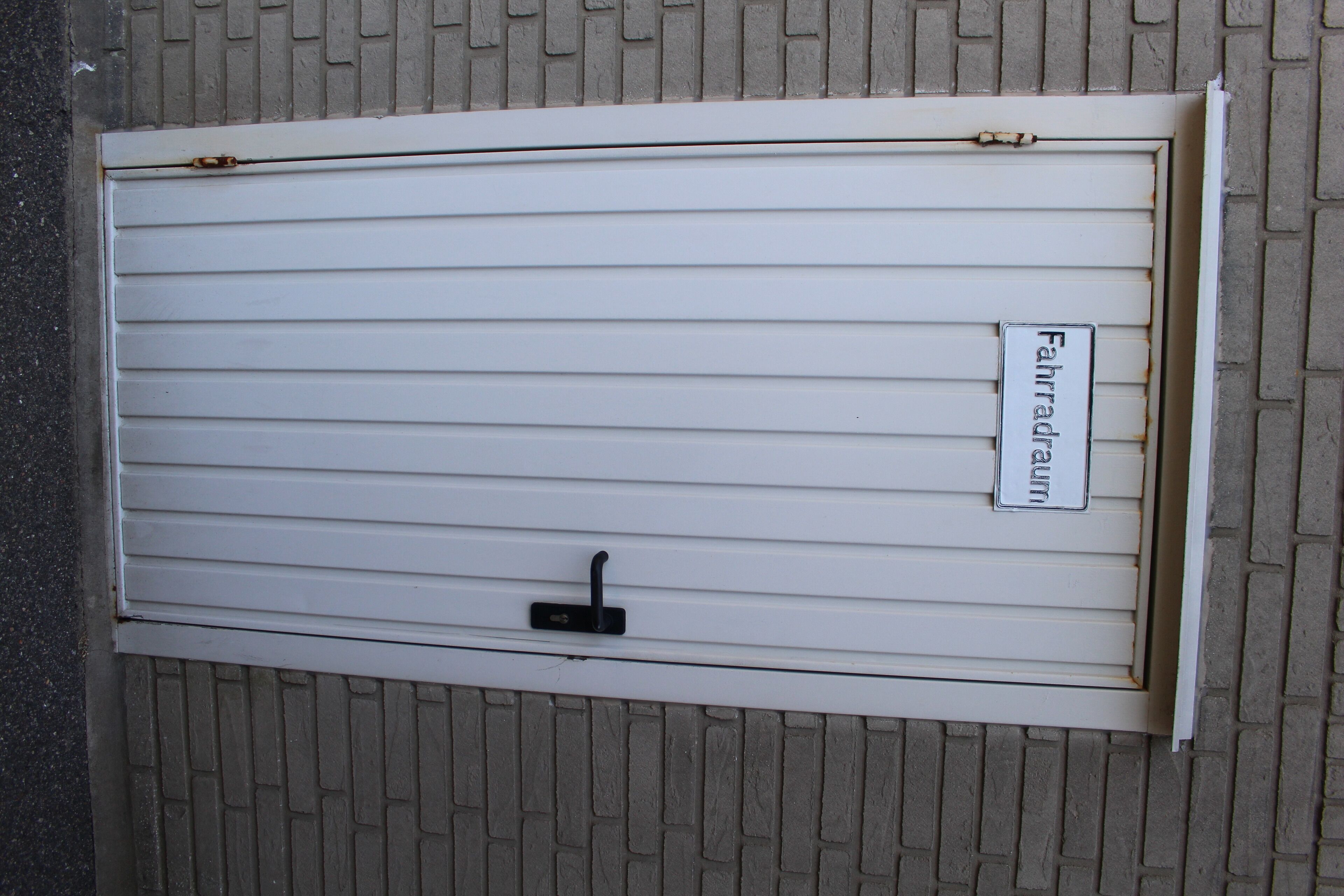 A closed window with a metal handle and a sign that reads "Fahrraum".