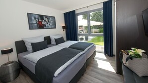 A modern hotel room with a large bed, a flat-screen TV, and a view of the outdoors.
