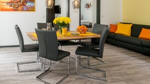A modern dining area with a wooden table, black chairs, and a vase of yellow flowers.