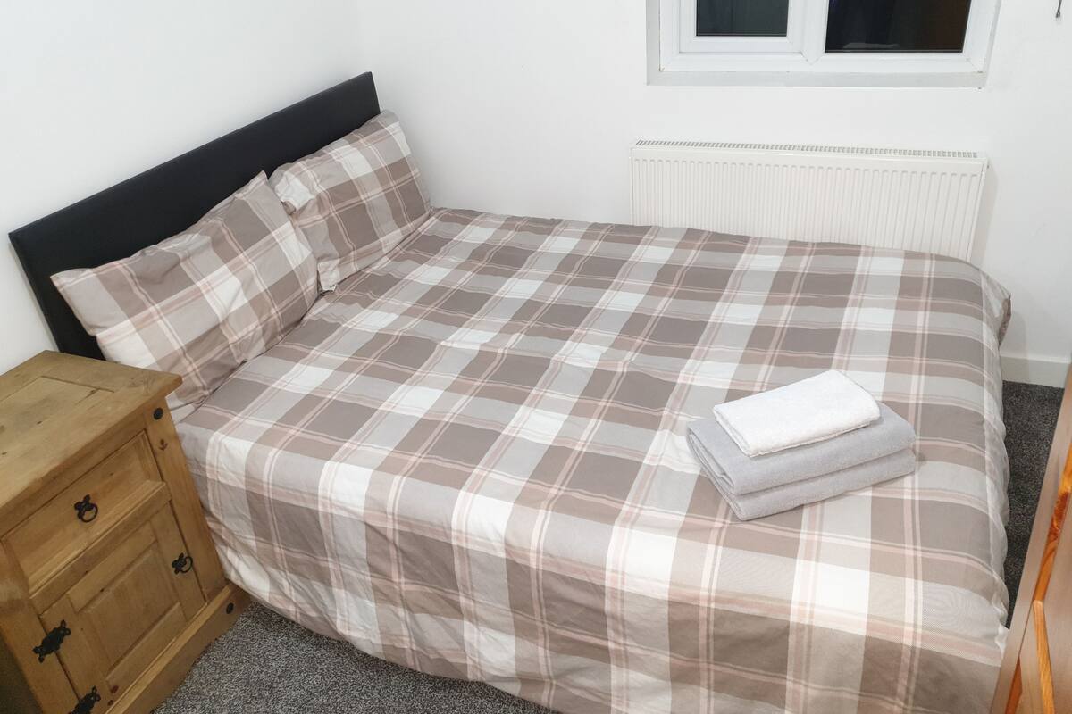 A bedroom with a bed, a wooden chest of drawers, and a radiator.