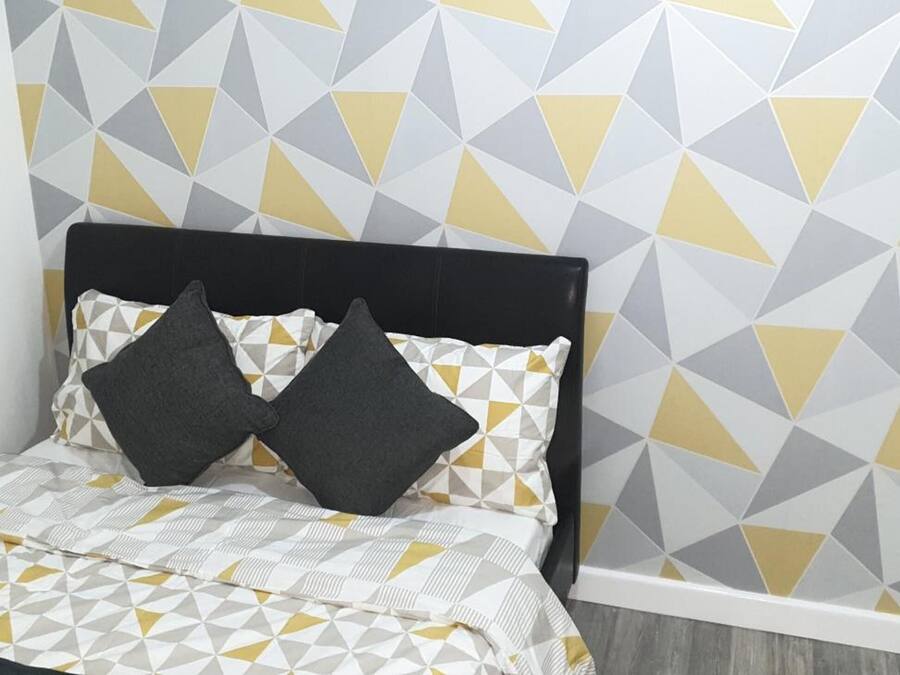 A bed with a geometric patterned bedspread, a black headboard, and two pillows.