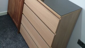 Un armario de madera con espejo y una mesita con un rollo de toallas de papel.